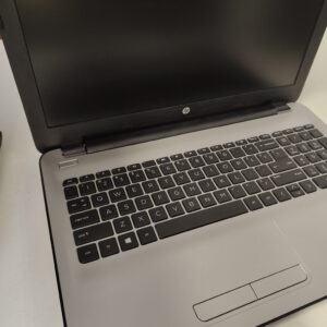 Open HP laptop with black keyboard and a blank laptop screen, angled on a light surface.